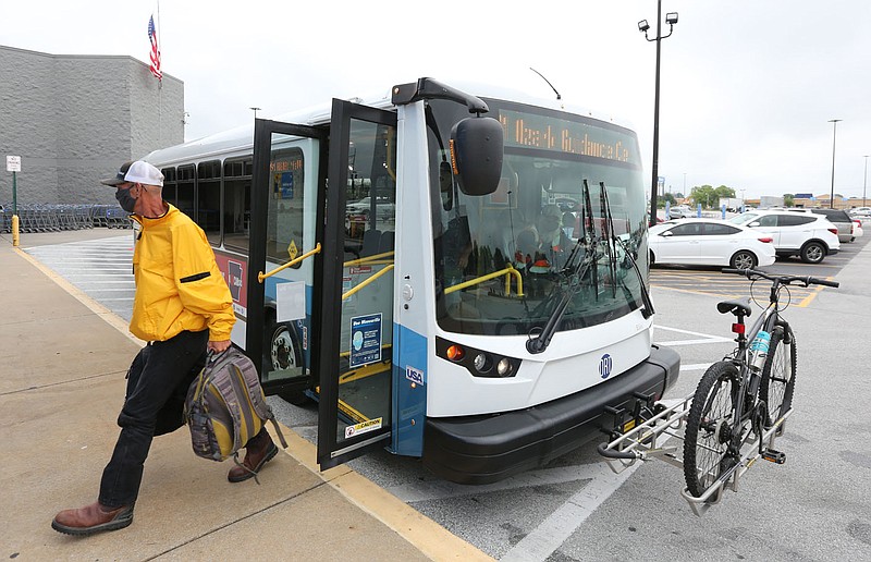 A passenger disembarks from the Route 61 Ozark Regional Transit bus Friday, July 2, 2021, in front of the Walmart Supercenter on Thompson Street in Springdale. On-demand public transit has been successful enough during a trial in Rogers that regional transit providers are considering expanding the service to other cities in the region. On-demand transport enables passengers to book their journey at a convenient time during service operating hours, and to be picked up from an agreed location. Riders have the option to book online or through an app and have a ride within a matter of minutes.       Check out nwaonline.com/210705Daily/ and nwadg.com/photos for a photo gallery.(NWA Democrat-Gazette/David Gottschalk)