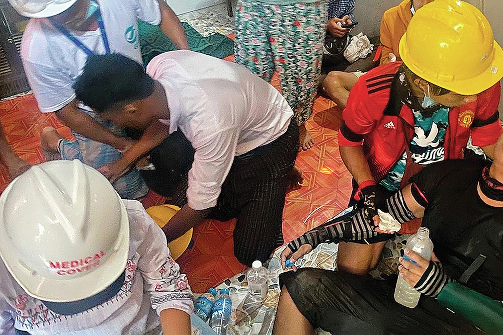 In this March 9, 2021 photo obtained by The Associated Press, doctors treat a wounded protester in a secret clinic set up in a resident's house in Yangon, Myanmar. In Myanmar, the military has declared war on health care _ and on doctors themselves, who were early and fierce opponents of the takeover in February. (AP Photo)