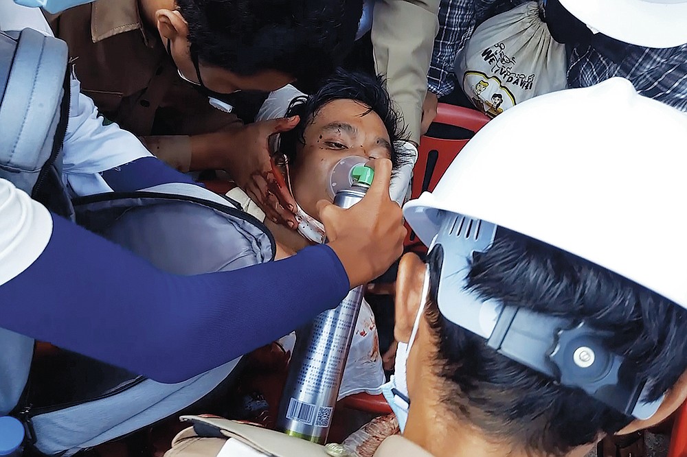 FILE - In this Sunday, Feb. 28, 2021 image from video provided by Dakkhina Insight, medics attend to a man who appeared to be wounded in his upper chest on a street in Dawei, Myanmar. In Myanmar, the military has declared war on health care _ and on doctors themselves, who were early and fierce opponents of the takeover in February. (Dakkhina Insight via AP)