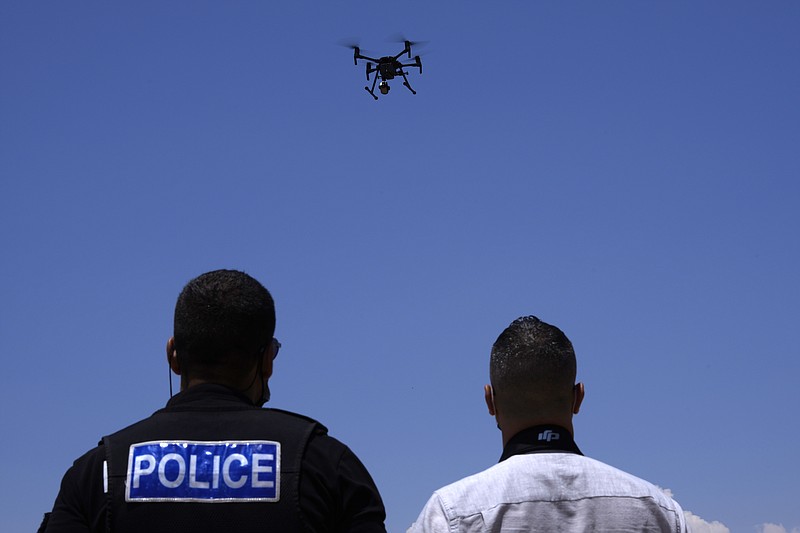 British police officers control a drone with cameras within the British military base, between Greek Cypriot, south, and Turkish Cypriots, north, near Dhekelia military base, Cyprus, Tuesday, July 6, 2021. Authorities at a British military base on Cyprus have doubled their customs officers and procured detection equipment as part of stepped-up efforts to thwart people trafficking from the breakaway north of the ethnically split island nation. (AP Photo/Petros Karadjias)
