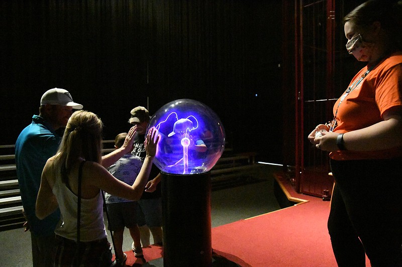 Izzy Saettele, educator at Mid-America Science Museum, watches Tesla show attendees explore the plasma ball. - Photo by Tanner Newton of The Sentinel-Record