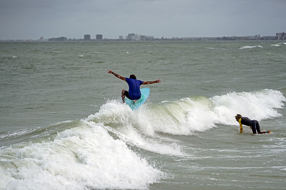 Luis Ernesto catches a small wave while surfing along Pass-a-Grille Beach, Wednesday, July 7, 2021 in St. Pete Beach, Fla., the morning after Tropical Storm Elsa moved over the Tampa Bay Area. (Martha Asencio-Rhine/Tampa Bay Times via AP)