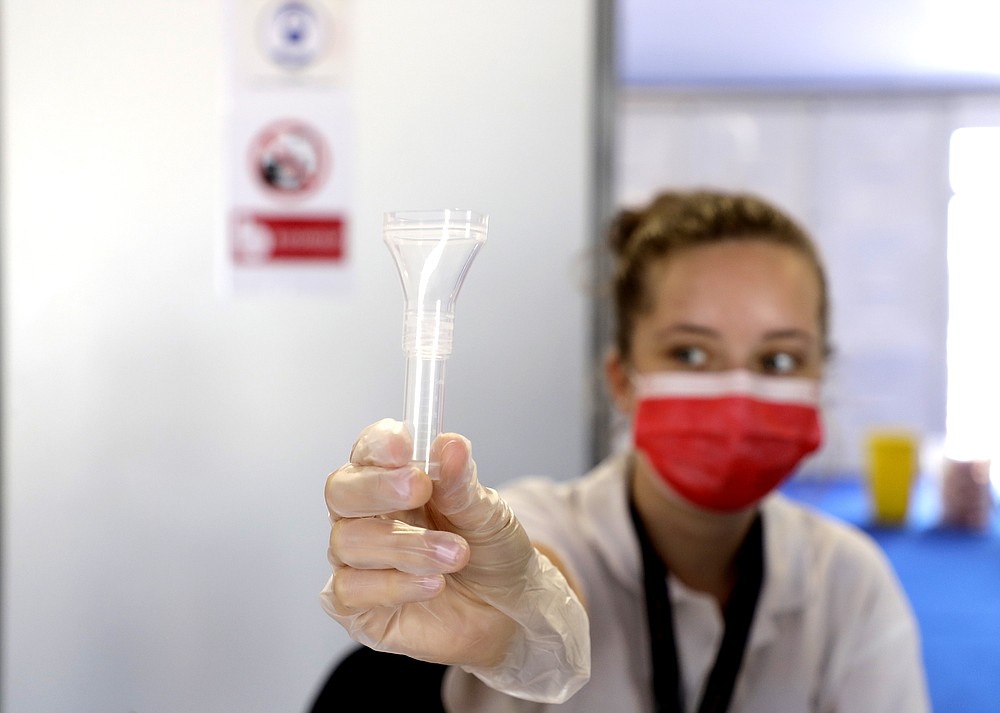 A festival worker holds a coronavirus specimen test at the 74th international film festival, Cannes, southern France, Tuesday, July 6, 2021. (Photo by Vianney Le Caer/Invision/AP)