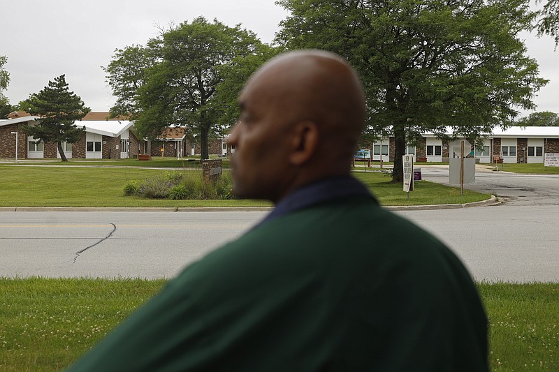 Crosby Smith, care provider at Ludeman Developmental Center, a state home for the developmentally disabled, looks towards the care center, Thursday, July 8, 2021 in Park Forest, Ill. Smith and his fiancee were among numerous staff and residents at the Ludeman Developmental Center who contracted the virus last year. He said the hazard money helped pay down credit cards and avoid further debt when buying clothing and shoes. (AP Photo/Shafkat Anowar)