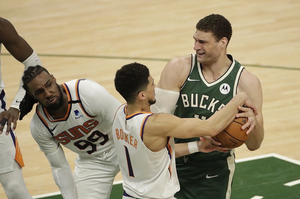 Milwaukee Bucks' Brook Lopez drives to the basket against Phoenix Suns' Devin Booker (1) and Jae Crowder (99) during the second half of Game 3 of basketball's NBA Finals, Sunday, July 11, 2021, in Milwaukee. (AP Photo/Aaron Gash)