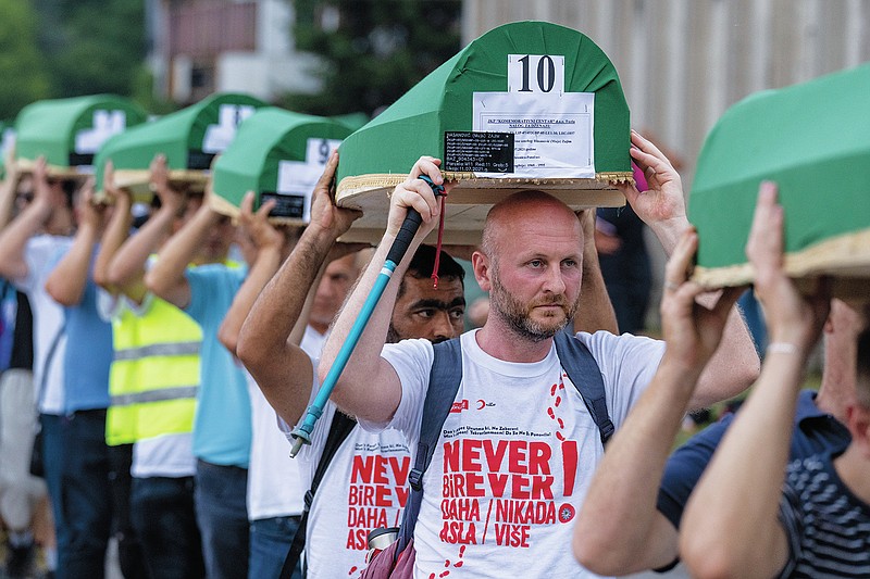 Mourners carry caskets of 19 identified victims which will be buried in Srebrenica on Sunday, in Potocari, Bosnia, Saturday, July 10, 2021. Bosnia commemorates more than 8,000 Bosnian Muslims men and boys who perished 26 years ago during 10 days of slaughter after Srebrenica was overrun by Bosnian Serb forces on July 11, 1995, during Bosnia's 1992-95 war. (AP Photo/Darko Bandic)