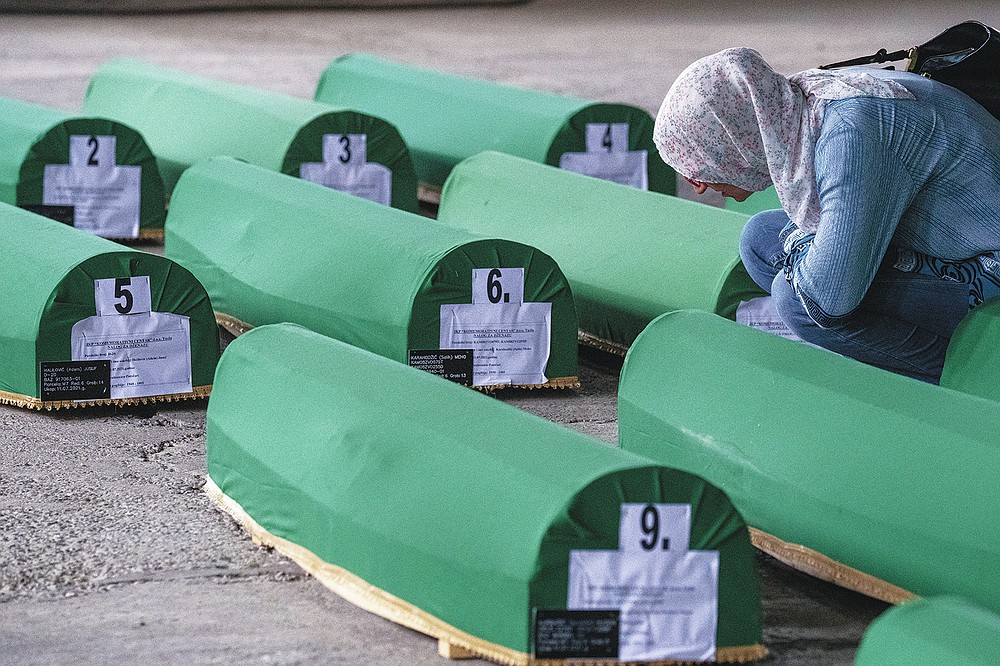 A woman inspect caskets of 19 identified victims which will be buried in Srebrenica on Sunday, in Potocari, Bosnia, Saturday, July 10, 2021. Bosnia commemorates more than 8,000 Bosnian Muslims men and boys who perished 26 years ago during 10 days of slaughter after Srebrenica was overrun by Bosnian Serb forces on July 11, 1995, during Bosnia's 1992-95 war. (AP Photo/Darko Bandic)