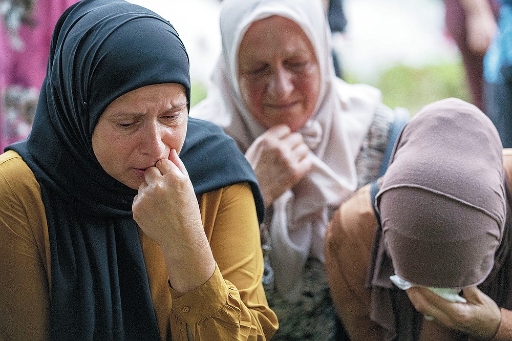 Women mourn next to bodies of 19 identified victims which will be buried in Srebrenica on Sunday, in Potocari, Bosnia, Saturday, July 10, 2021. Bosnia commemorates more than 8,000 Bosnian Muslims men and boys who perished 26 years ago during 10 days of slaughter after Srebrenica was overrun by Bosnian Serb forces on July 11, 1995, during Bosnia's 1992-95 war. (AP Photo/Darko Bandic)