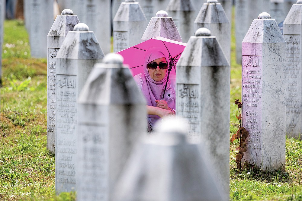 A woman visits the memorial cemetery in Potocari near Srebrenica, Bosnia, Sunday, July 11, 2021. Bosnia is marking the 26th anniversary of the Srebrenica massacre, the only episode of its 1992-95 fratricidal war that has been declared a genocide by international and national courts. The brutal execution of more than 8,000 Muslim Bosniaks by Bosnian Serb troops is being commemorated by a series of events Sunday. (AP Photo/Darko Bandic)