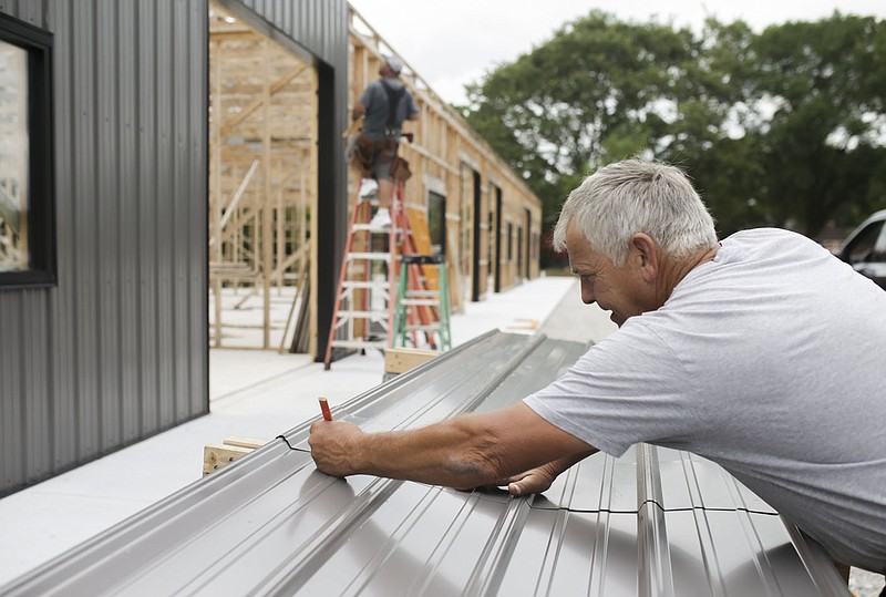 Raymond Barett of Bentonville measures a sheet of metal to cover the frame of a building, Monday, July 12, 2021 at a private property along Springvalley Rd. in Bentonville. Raymond Barett is building properties to lease out to private businesses as an income source. Check out nwaonline.com/210713Daily/ for today's photo gallery. 
(NWA Democrat-Gazette/Charlie Kaijo)