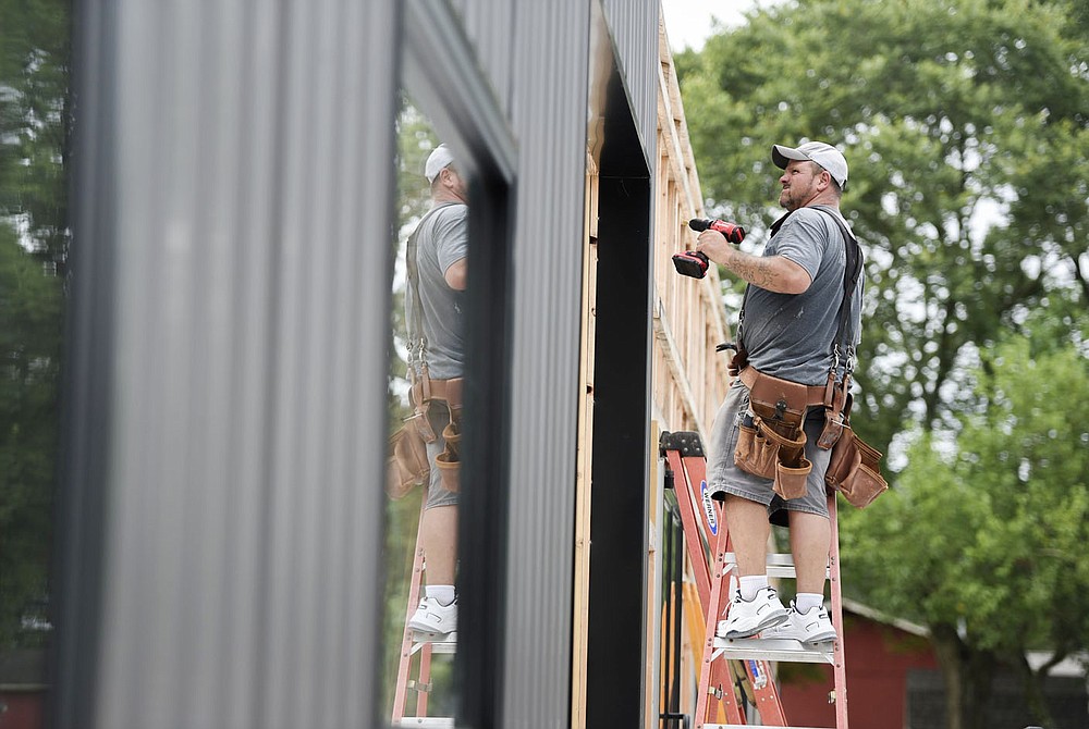 Dave Evans of Bentonville screws metal sheeting to the frame of a building, Monday, July 12, 2021 at a private property along Springvalley Rd. in Bentonville. Raymond Barett is building properties to lease out to private businesses as an income source. Check out nwaonline.com/210713Daily/ for today's photo gallery.
(NWA Democrat-Gazette/Charlie Kaijo)