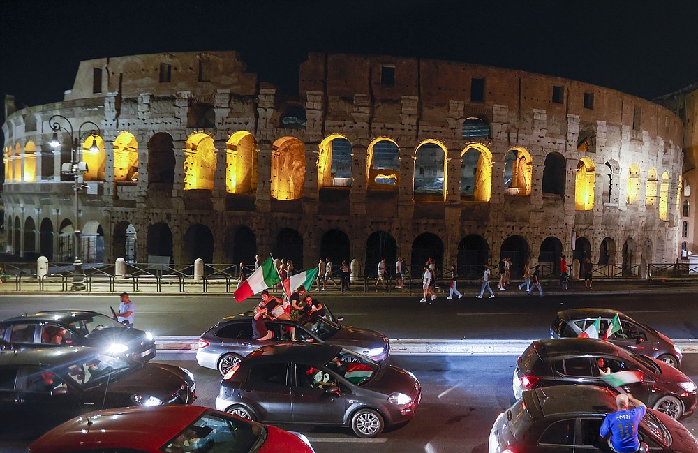 I tifosi italiani festeggiano davanti all'antico Colosseo a Roma, lunedì 12 luglio 2021, dopo che l'Italia ha battuto l'Inghilterra per vincere il Campionato Europeo di Calcio 2020 nella partita finale tenutasi allo stadio di Wembley a Londra.  L'Italia ha battuto l'Inghilterra 3-2 ai rigori dopo l'1-1.  (Foto AP/Riccardo De Luca)