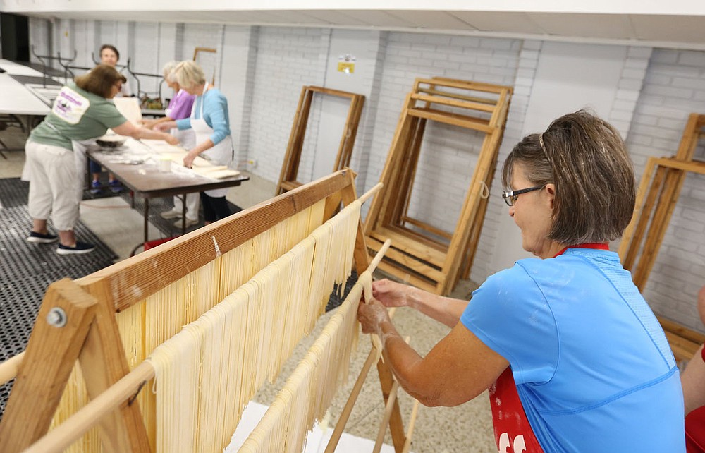 Elaine Sbanotto hangs pasta noodles on a rack for drying Monday, July 19, 2021, at the St. Joseph's Parish Hall in Tontitown. More than 3,000 pounds of pasta noodles are being prepared for the 122nd Tontitown Grape Festival which runs Tuesday, August 3 through Saturday, August 7. The homemade spaghetti will be served August 5 through 7. Check out nwaonline.com/210801Daily/ and nwadg.com/photos for a photo gallery.(NWA Democrat-Gazette/David Gottschalk)