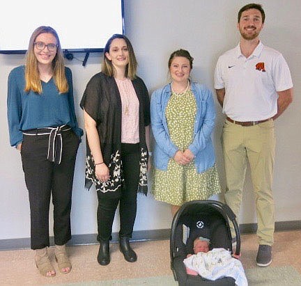 Westside Eagle Observer/SUSAN HOLLAND
Four newly hired faculty members pose just after being introduced by Superintendent Maribel Childress at the June 21 meeting of the Gravette school board. New hires pictured are Tanner Gilliaum, middle school social studies teacher/assistant volleyball coach; Melody Kwok, administrative specialist for communications and technology; Morgan Knuckles, Glenn Duffy Elementary and Upper Elementary art teacher, and her baby daughter; and Drew Pasley, elementary p.e. teacher/assistant basketball coach.