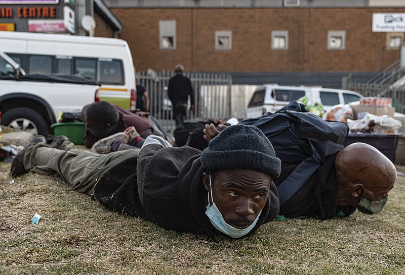 Suspect looters are held at the Bara taxi rank shops in Soweto, Johannesburg, Monday, July 12, 2021. Police say six people are dead and more than 200 have been arrested amid escalating violence during rioting that broke out following the imprisonment of South Africa's former President Jacob Zuma. (AP Photo/Ali Greeff)