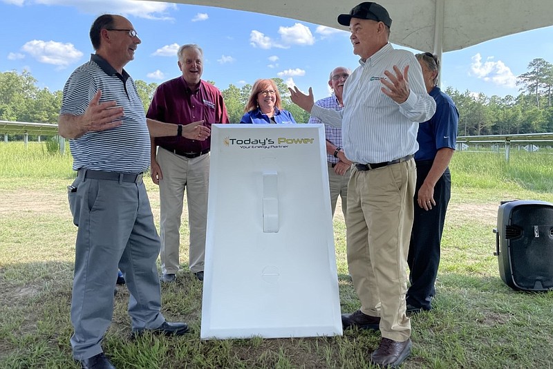 Hampton Schools Superintendent Doug Worley, left, and Ouachita Electric CEO and General Manager Mark Cayce, gesture after flipping a large display switch Wednesday to signify that the school district's new solar array is operable. (Jennah Denney/Today's Power)