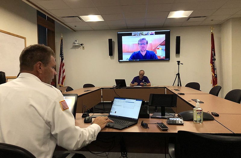Brad Hardin (left), Fayetteville fire chief, prepares Wednesday, July 14, 2021, for a hybrid in-person and online meeting of the city's Board of Health while Fayetteville Mayor Lioneld Jordan also gets ready for the meeting. The board discussed recommendations for masking in light of the delta variant of covid-19. (NWA Democrat-Gazette/Stacy Ryburn)