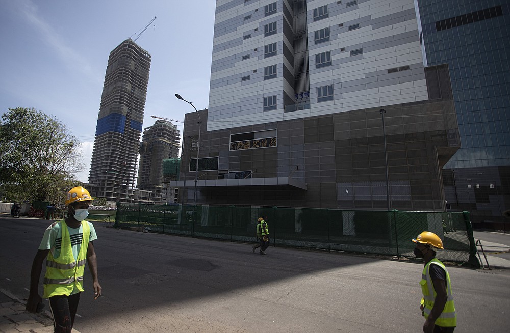 Indian workers employed at an Indian invested development project walk outside their construction site in Colombo, Sri Lanka on June 16, 2021. Sri Lanka has cut back on imports of farm chemicals, cars and even its staple spice turmeric as its foreign exchange reserves dwindle, hindering its ability to repay a mountain of debt as the South Asian island nation struggles to recover from the pandemic. (AP Photo/Eranga Jayawardena)