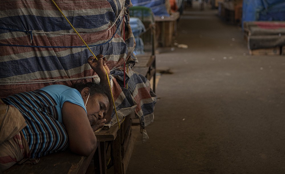 A Sri Lankan vegetable vendor sleeps by her stall at a wholesale vegetable market closed to curb the spread of the coronavirus in Colombo, Sri Lanka on June 16, 2021. Sri Lanka has cut back on imports of farm chemicals, cars and even its staple spice turmeric as its foreign exchange reserves dwindle, hindering its ability to repay a mountain of debt as the South Asian island nation struggles to recover from the pandemic. (AP Photo/Eranga Jayawardena)