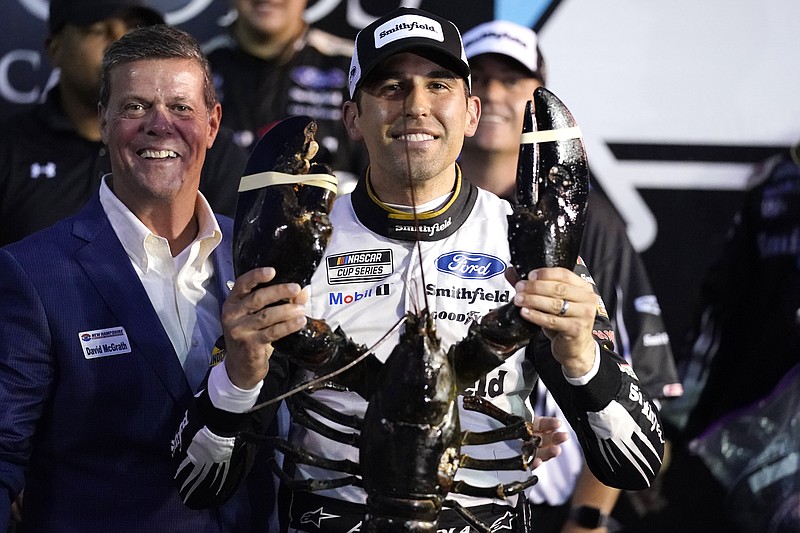 Aric Almirola smiles as he holds up a giant lobster after winning the NASCAR Cup Series auto race Sunday, July 18, 2021, in Loudon, N.H. At left is Dave McGrath, general manager of New Hampshire Motor Speedway. (AP Photo/Charles Krupa)