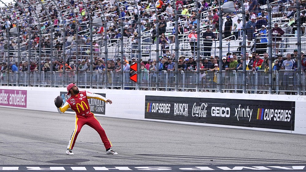 Driver Bubba Wallace throws a football to fans during a rain delay at the NASCAR Cup Series auto race Sunday, July 18, 2021, in Loudon, N.H. (AP Photo/Charles Krupa)