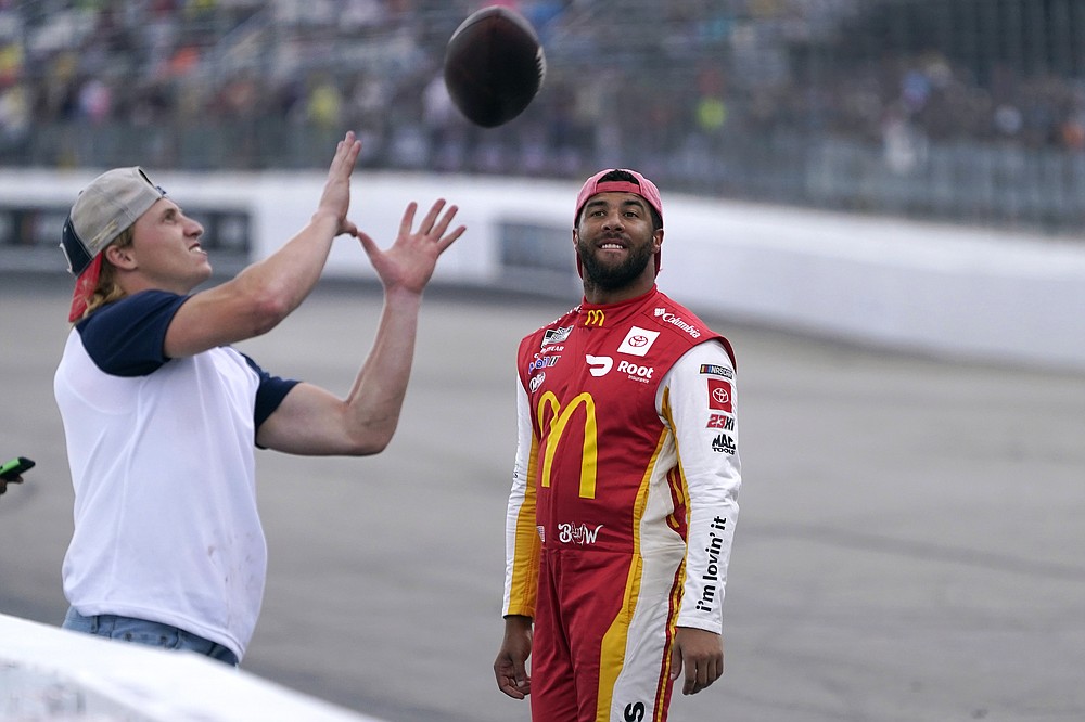 Bubba Wallace, right, smiles as he watches New England Patriots wide receiver Gunner Olszewski catch a soccer ball thrown by a fan during a rain delay during the NASCAR Cup Series auto race on Sunday, July 18 2021 in Loudon, NH (AP Photo / Charles Krupa)