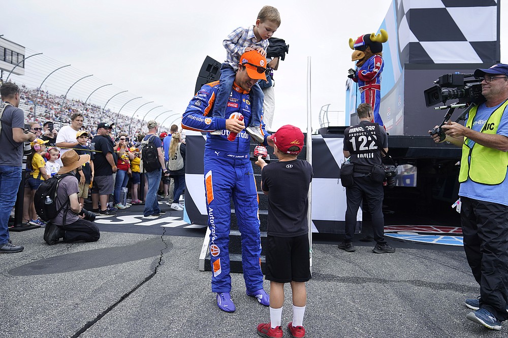 With son Hudson on his shoulders, Joey Logano stops to sign an autograph for a young fan before the NASCAR Cup Series auto race Sunday, July 18, 2021, in Loudon, N.H. (AP Photo/Charles Krupa)