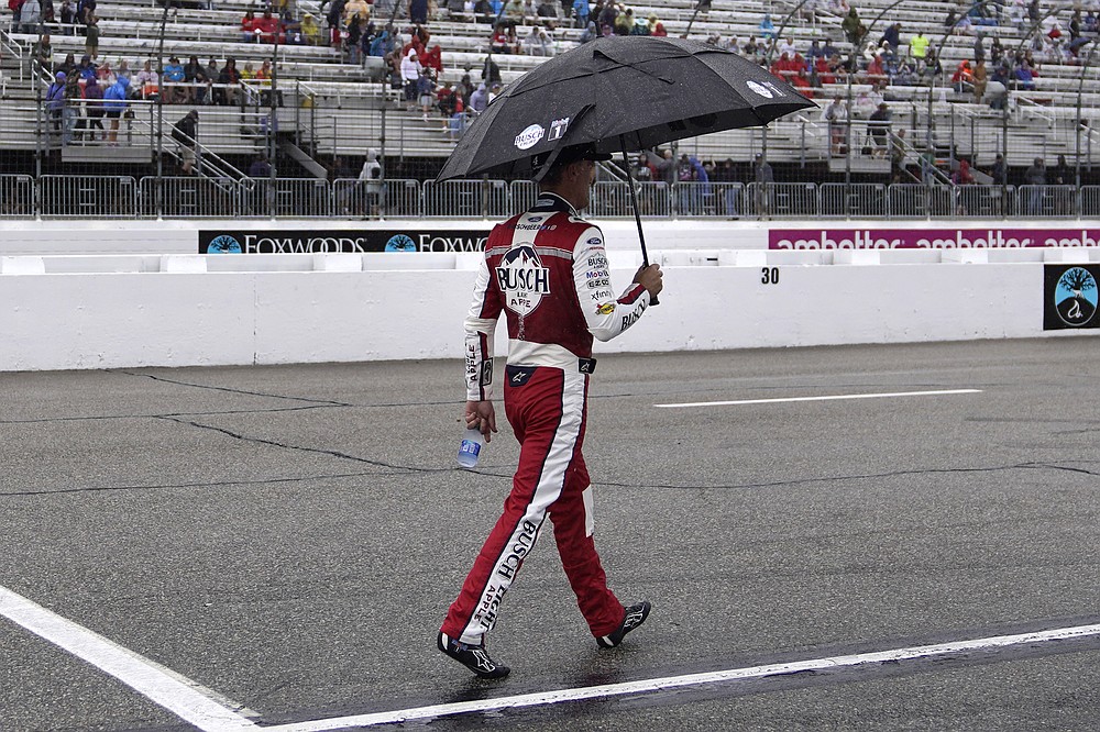 Kevin Harvick walks down pit road under an umbrella during a rain delay in the NASCAR Cup Series auto race Sunday, July 18, 2021, in Loudon, N.H. (AP Photo/Charles Krupa)