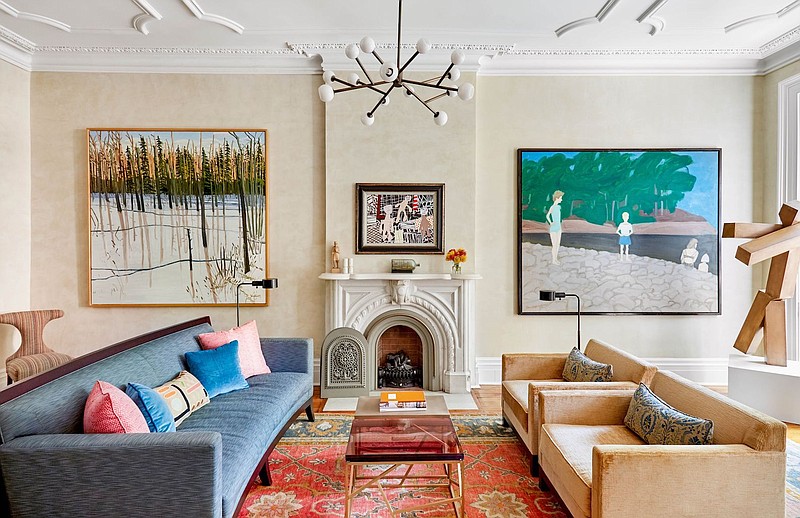 For this circa 1900 West Village townhome in New York, interior designer Kathleen Walsh designed the living room around a vibrant area rug. The bluish-green upholstered sofa and apricot-taupe chairs draw from secondary colors in the rug. The wall art also relates to the blues and tans in the rug. (Courtesy Rikki Snyder for Kathleen Walsh Interiors)