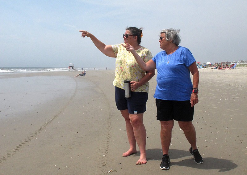 Suzanne Hornick, left, and Susan Cox, right, look out to sea from a beach in Ocean City N.J. on July 8, 2021 where power cables from an offshore wind farm are projected to come ashore. They are among opponents of offshore wind who question its impact on the ocean, the environment and the economy. (AP Photo/Wayne Parry)