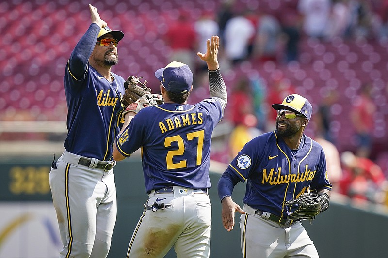 Milwaukee Brewers' Jace Peterson (14) celebrates with Willy Adames (27) after the team's win over the Cincinnati Reds in a baseball game in Cincinnati, Sunday, July 18, 2021. (AP Photo/Bryan Woolston)