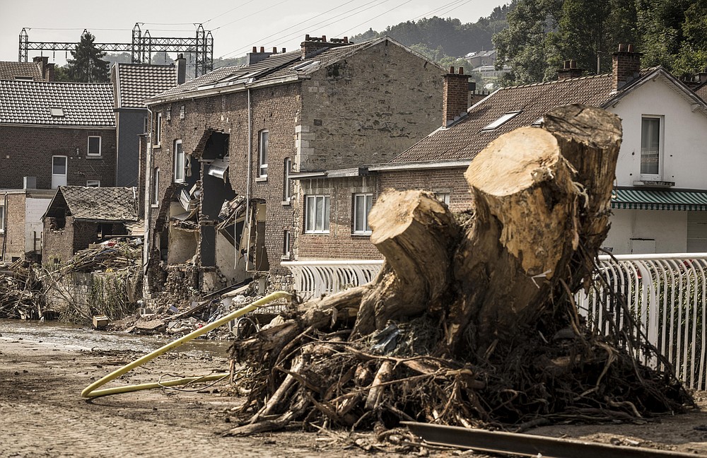 A large tree stump stands in the street among damaged houses in Pepinster, Belgium, Monday, July 19, 2021. Residents in several provinces continued to clean up after severe flooding in Germany and Belgium turned streams and streets into raging torrents that swept away cars and caused houses to collapse. (AP Photo/Valentin Bianchi)