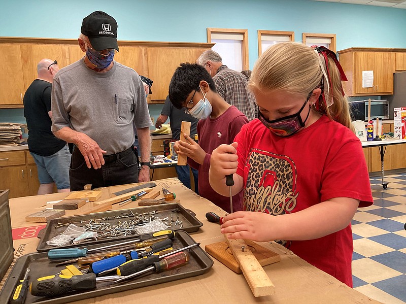 Tools 101 presenter Pat Freeman, left, works with Aariz Sorker and Ella Herring at the screwdriver demonstration. It was part of an event by the White Hall Friends of the Library. (Special to The Commercial/White Hall Friends of the Library)