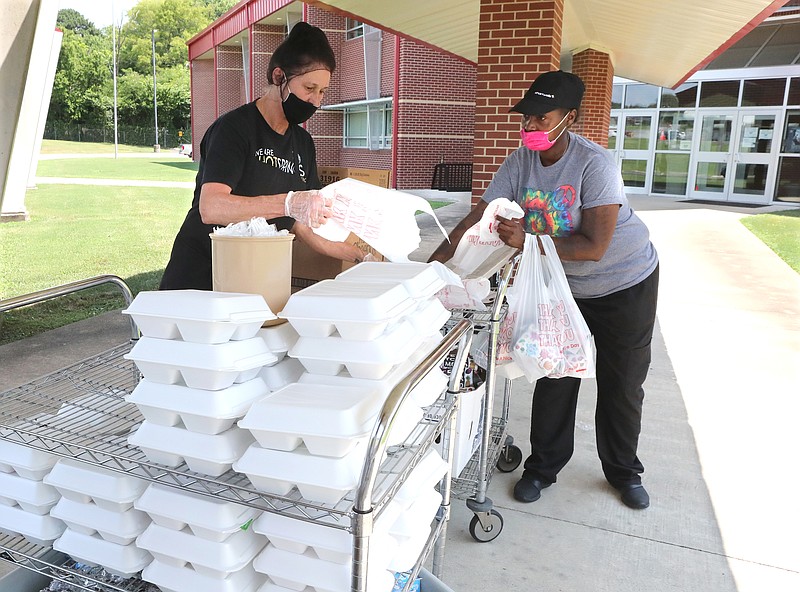 Park Magnet School employees Lesa Thomas, left, and Renica Chunn prepare summer lunch meals for students at a drive-up location at the school on July 8. - Photo by Richard Rasmussen of The Sentinel-Record