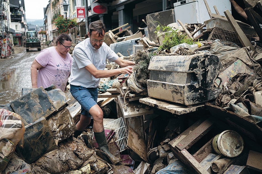 Priest Joerg Meyrer walks over debris in Bad Neuenahr-Ahrweiler, Germany, Monday July 19, 2021. More than 180 people died when heavy rainfall turned tiny streams into raging torrents across parts of western Germany and Belgium, and officials put the death toll in Ahrweiler county alone at 110. (AP Photo/Bram Janssen)