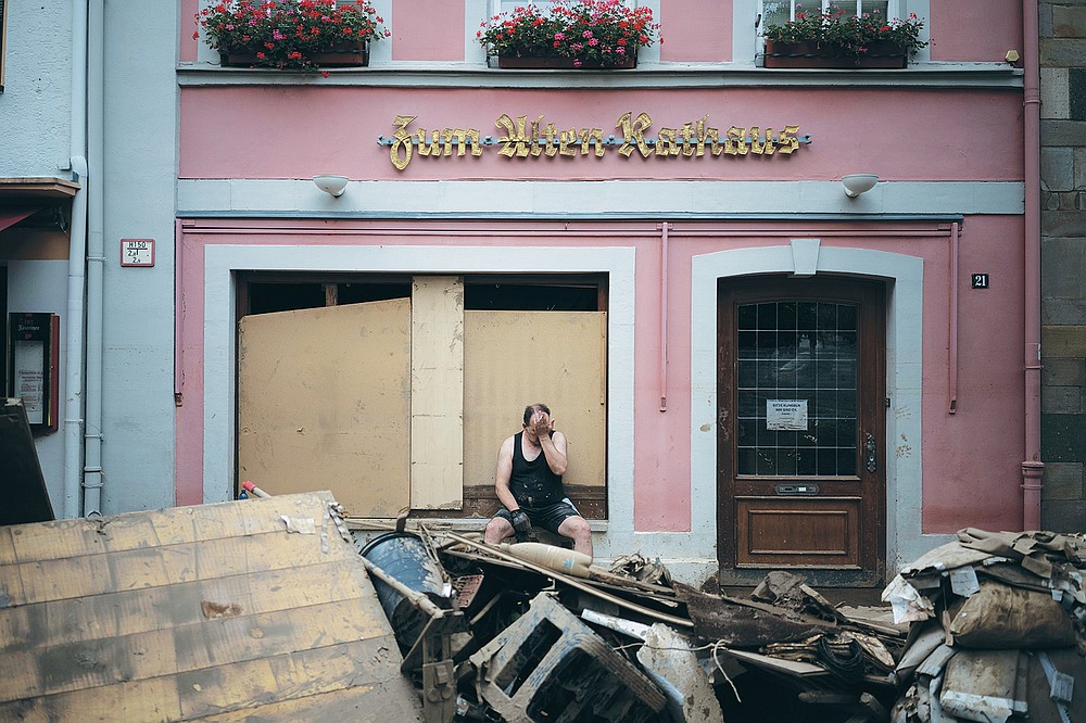 A man takes a break from cleaning up debris from the flood disaster in Bad Neuenahr-Ahrweiler, Germany, Monday July 19, 2021. More than 180 people died when heavy rainfall turned tiny streams into raging torrents across parts of western Germany and Belgium, and officials put the death toll in Ahrweiler county alone at 110. (AP Photo/Bram Janssen)