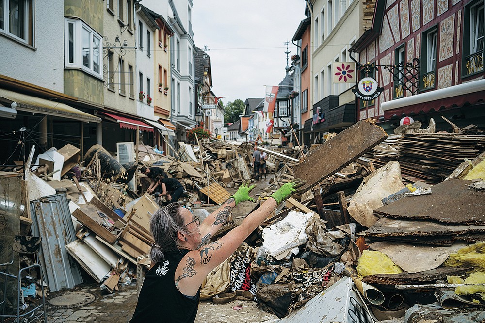 A woman throws away rubbish in the center of Bad Neuenahr-Ahrweiler, Germany, Monday July 19, 2021. More than 180 people died when heavy rainfall turned tiny streams into raging torrents across parts of western Germany and Belgium, and officials put the death toll in Ahrweiler county alone at 110. (AP Photo/Bram Janssen)