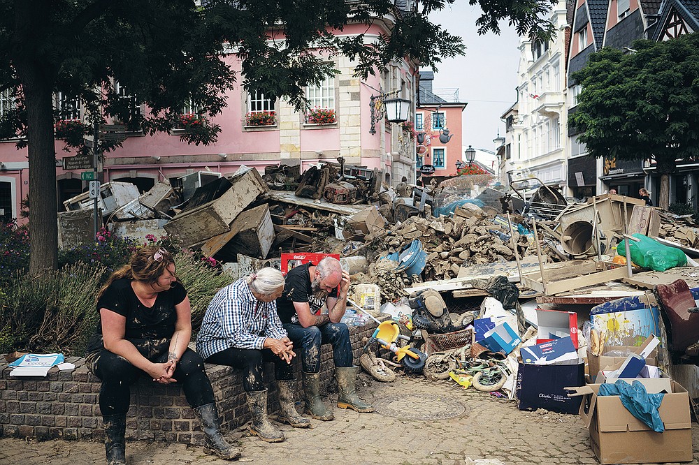 People rest from cleaning up the debris of the flood disaster in Bad Neuenahr-Ahrweiler, Germany, Monday July 19, 2021. More than 180 people died when heavy rainfall turned tiny streams into raging torrents across parts of western Germany and Belgium, and officials put the death toll in Ahrweiler county alone at 110. (AP Photo/Bram Janssen)
