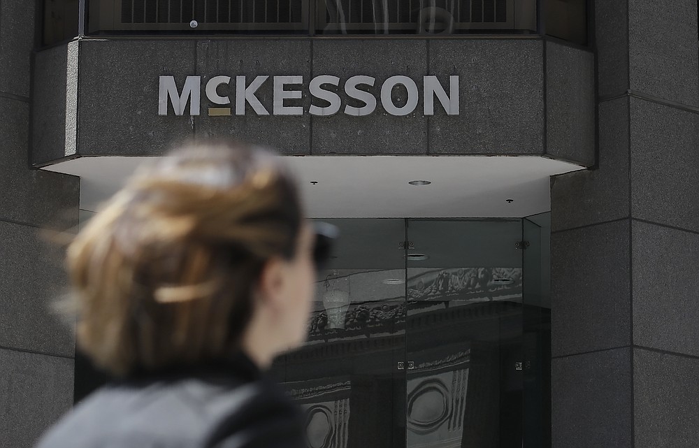 FILE - In this July 17, 2019, file photo, a pedestrian passes a McKesson sign on an office building in San Francisco. A $26 billion settlement between the three biggest U.S. drug distribution companies and drugmaker Johnson & Johnson and thousands of states and municipalities that sued over the toll of the opioid crisis is certainly significant, but it is far from tying a neat bow on the tangle of still unresolved lawsuits surrounding the epidemic. (AP Photo/Jeff Chiu, File)