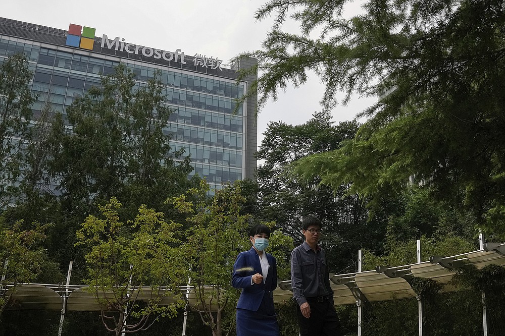People walk through a park near the Microsoft office building in Beijing, Tuesday, July 20, 2021. The Biden administration and Western allies formally blamed China on Monday for a massive hack of Microsoft Exchange email server software and asserted that criminal hackers associated with the Chinese government have carried out ransomware and other illicit cyber operations. (AP Photo/Andy Wong)