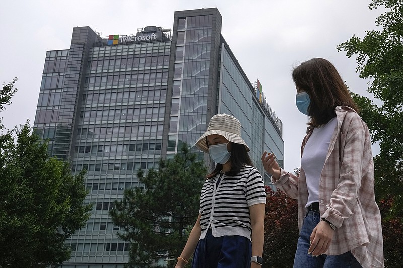 Women wearing face masks to help curb the spread of the coronavirus walk by the Microsoft office building in Beijing, Tuesday, July 20, 2021. The Biden administration and Western allies formally blamed China on Monday for a massive hack of Microsoft Exchange email server software and asserted that criminal hackers associated with the Chinese government have carried out ransomware and other illicit cyber operations. (AP Photo/Andy Wong)