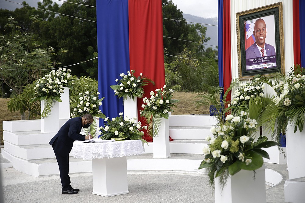 A man puts his name into a signature book during a memorial ceremony for late Haitian President Jovenel Moise at the National Pantheon Museum in Port-au-Prince, Haiti, Tuesday, July 20, 2021. Moise was assassinated on July 7 at his home. (AP Photo/Joseph Odelyn)