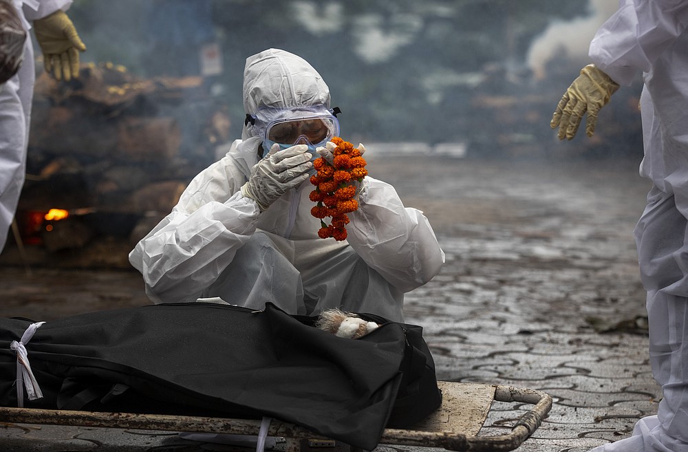 FILE - In this July 2, 2021 file photo, a relative performs last rites before the cremation of a COVID-19 victim in Gauhati, India. India's excess deaths during the pandemic could be a staggering 10 times the official COVID-19 toll, likely making it modern India's worst human tragedy, according to the most comprehensive research yet on the ravages of the virus in the south Asian country. (AP Photo/Anupam Nath, File)