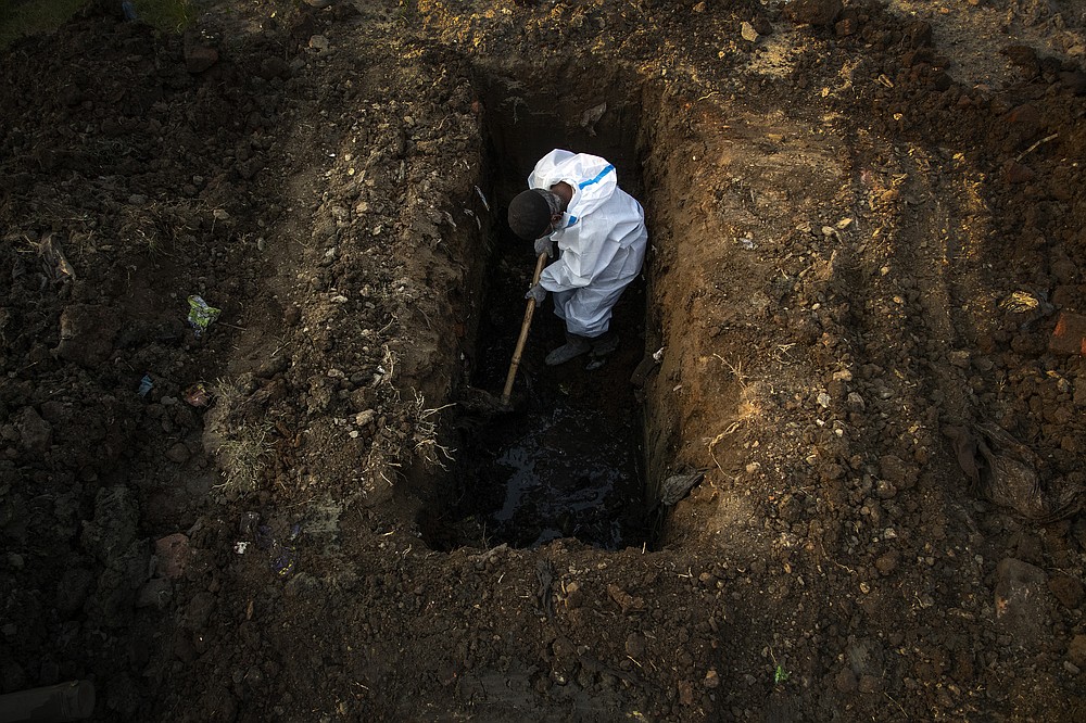 FILE - In this April 25, 2021, file photo, a man in protective suit digs earth to bury the body of a person who died of COVID-19 in Gauhati, India. India's excess deaths during the pandemic could be a staggering 10 times the official COVID-19 toll, likely making it modern India's worst human tragedy, according to the most comprehensive research yet on the ravages of the virus in the south Asian country. (AP Photo/Anupam Nath, File)