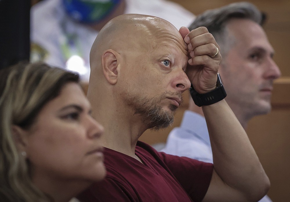Champlain Towers South tenant Paolo Longobardi, center, listens closely as other residents share their grief and thoughts regarding the future of the Champlain Towers South site via Zoom, during a hearing, Wednesday, July 21, 2021, in Miami. Judge Michael Hanzman said victims and families who suffered losses in the collapse of the 12-story oceanfront Florida condominium will get a minimum of $150 million in compensation initially. (Carl Juste/Miami Herald via AP, Pool)