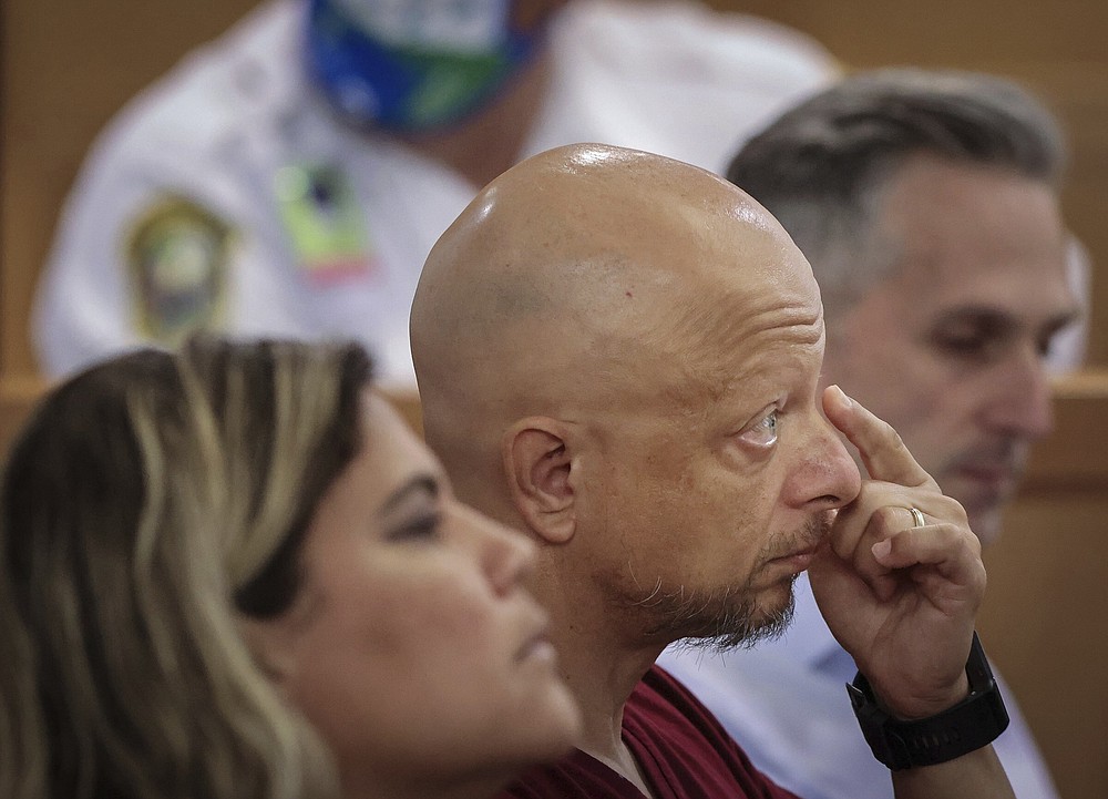 Champlain Towers South tenant Paolo Longobardi, center, listens closely as other residents share their grief and thoughts regarding the future of the Champlain Towers South site via Zoom, during a hearing, Wednesday, July 21, 2021, in Miami. Judge Michael Hanzman said victims and families who suffered losses in the collapse of the 12-story oceanfront Florida condominium will get a minimum of $150 million in compensation initially. (Carl Juste/Miami Herald via AP, Pool)