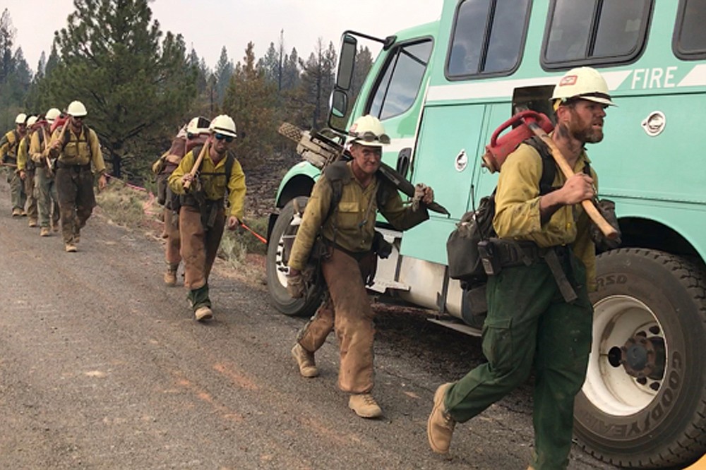 In this photo provided by the Bootleg Fire Incident Command, a handcrew walks to engage the Bootleg Fire in southern Oregon on Monday, July 19, 2021. The Oregon fire has ravaged the southern part of the state and has been expanding by up to 4 miles (6 kilometers) a day, pushed by gusting winds and critically dry weather that's turned trees and undergrowth into a tinderbox. (Bootleg Fire Incident Command via AP)