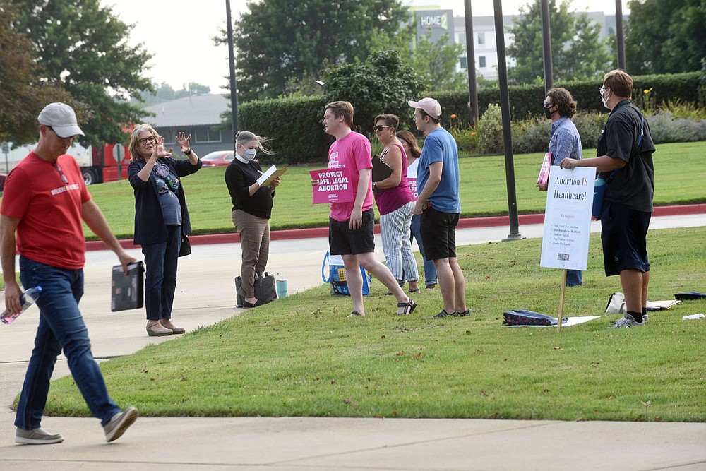 People entering the Benton County Quorum Court committee of the whole meeting Tuesday July 20 2021 walk past sign carriers at Northwest Arkansas Community College where the meeting was held.
(NWA Democrat-Gazette/Flip Putthoff)