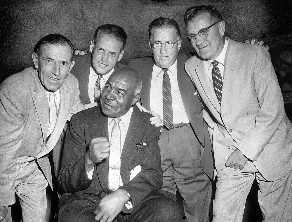 Judge Fred W. "Duke" Slater, seated, of University of Iowa's undefeated football team of 1921, huddles with former teammates at a luncheon honoring him on Aug, 13, 1958, at the Sherman Hotel in Chicago. Other players are, from left, Aubrey Devine, Les Belding, Bill Kelly and Glen Devine. (Chicago Tribune via AP)