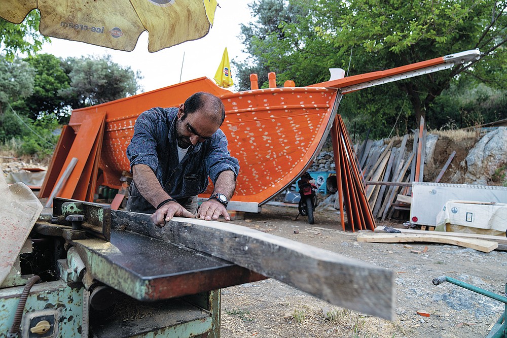 Giorgos Kiassos, one of the last remaining boatbuilders on Samos island, uses a hand plane to shape wood to be used for the frame of a traditional boat on Thursday, June 10, 2021, at his mountain boatyard in the village of Drakaioi. The art of designing and building these vessels, which is done entirely by hand, is under threat. Fewer wooden boats are being ordered, with plastic and fiberglass ones cheaper to maintain. (AP Photo/Petros Giannakouris)